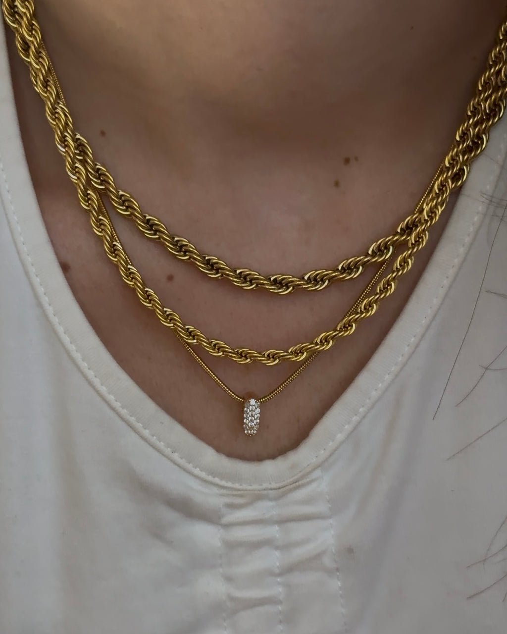 Collana in acciaio inossidabile con ciondolo dorato in ottone e zirconi scintillanti, stile moderno.